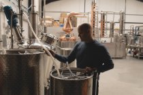 Operaio che riempie bevanda alcolica in tamburo in fabbrica — Foto stock