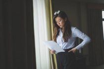 Бізнес-леді читання документа біля вікна в готельному номері — стокове фото