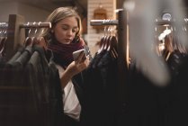 Menina bonita usando telefone celular enquanto faz compras no shopping — Fotografia de Stock