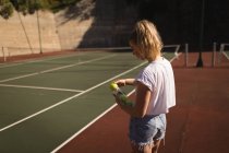 Junge Frau entfernt Tennisball aus Tennisballkoffer — Stockfoto