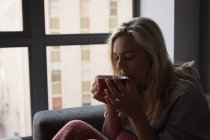 Жінка має каву у вітальні вдома — стокове фото