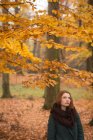 Mujer parada en el parque durante el otoño - foto de stock