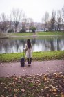 Rear view of businesswoman with baggage standing near lakeside — Stock Photo