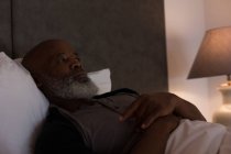 Старший мужчина, лежащий в спальне дома — стоковое фото
