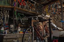 Mecânico feminino examinando uma bicicleta na oficina — Fotografia de Stock