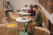 Ejecutiva masculina usando laptop en la cafetería de la oficina - foto de stock