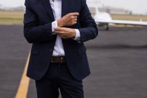 Mid section of businessman buttoning his shirt sleeves on a runaway — Stock Photo