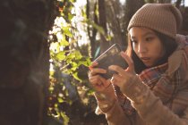 Жінка використовує мобільний телефон в лісі — стокове фото