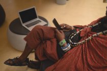 Низкая часть масаи человек в традиционной одежде с помощью мобильного телефона — стоковое фото