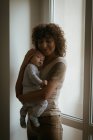 Mãe afetuosa abraçando seu bebê em casa — Fotografia de Stock
