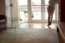 Cropped view of woman standing in sunlight in living room interior. — Stock Photo
