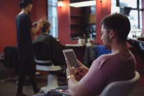 Cliente masculino usando tableta digital en la barbería - foto de stock