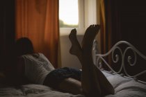 Vista trasera de la mujer acostada en la cama en casa - foto de stock