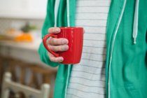 Mid section of man holding coffee mug at home — Stock Photo