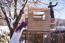 Frères et sœurs jouant dans une aire de jeux enneigée pendant l'hiver — Photo de stock