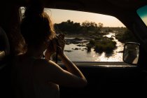 Mulher tirando foto da natureza com câmera digital no carro — Fotografia de Stock