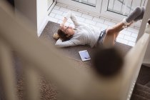 Mujer pensativa relajándose cerca de la ventana en casa - foto de stock