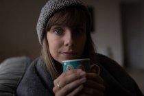 Frau in Wollmütze mit Kaffeebecher, Portrait. — Stockfoto