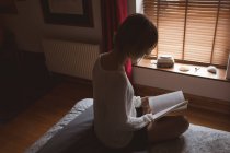 Mulher lendo livro na cama no quarto em casa — Fotografia de Stock