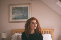Продумана жінка сидить на ліжку в спальні вдома — стокове фото