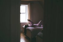Женщина с мобильного телефона, лежа на кровати в спальне дома — стоковое фото