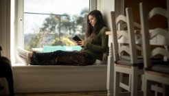 Жінка використовує мобільний телефон вдома — стокове фото
