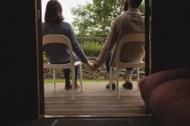 Rear view of couple holding hands while sitting on chairs — Stock Photo