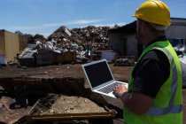 Rear view of worker using his laptop in the junkyard — Stock Photo