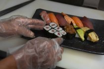 Крупный план шеф-повара, готовящего суши в подносе ресторана — стоковое фото