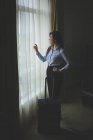 Femme d'affaires regardant par la fenêtre dans la chambre d'hôtel — Photo de stock
