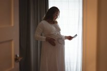 Pregnant woman looking at her sonography report while touching her stomach — Stock Photo