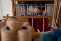 Partie médiane de la femme âgée tissant de la soie à la boutique — Photo de stock