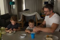 Père et fils prenant le petit déjeuner sur une table à manger à la maison — Photo de stock