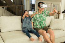 Pai e filha usando fone de ouvido realidade virtual em casa — Fotografia de Stock