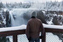 Vue arrière de l'homme regardant la cascade pendant l'hiver — Photo de stock