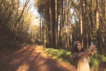 Женщина делает селфи с мобильного телефона в лесу — стоковое фото
