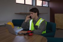 Работник мужского пола разговаривает по мобильному телефону за столом в офисе — стоковое фото