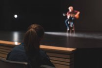 Frau beobachtet Musikerin beim Gitarrespielen auf der Bühne im Theater. — Stockfoto