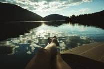 Baixa seção de homem relaxante em um barco em um lago — Fotografia de Stock