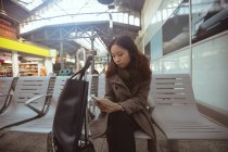 Жінка використовує мобільний телефон у зоні очікування на залізничній станції — стокове фото
