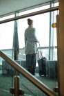 Задумчивая деловая женщина, стоящая с багажом в номере отеля — стоковое фото