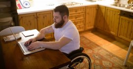 Молодий чоловік з обмеженими можливостями використовує ноутбук вдома — стокове фото