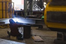Rear view of welder repairing metal frame in workshop — Stock Photo