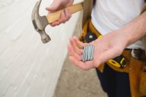 Mid section of male carpenter holding hammer and nails — Stock Photo
