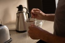 Seniorin rührt zu Hause in Küche Kaffee an — Stockfoto