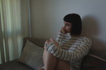 Femme inquiète assise sur le canapé dans le salon à la maison — Photo de stock