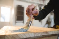 Carpintero masculino pintando una mesa en taller - foto de stock