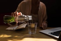 Mid section of woman pouring mint water into glass at cafe. — Stock Photo