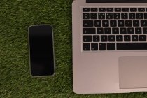 Primo piano di laptop e telefono cellulare su erba artificiale — Foto stock