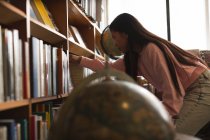 Вид сбоку девочки-подростка, выбирающей книгу в библиотеке — стоковое фото